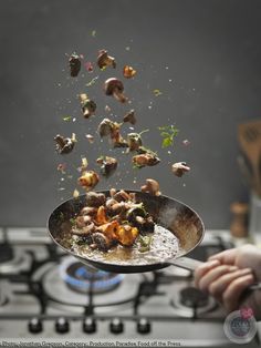 a person holding a frying pan full of food over a stove top burner