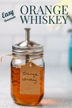 an orange whiskey in a glass jar with a tag on the front and back of it