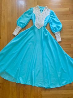 "Stunning 1970s turquoise Gunne Sax style full circle maxi dress 💎 Features V neck with beautiful lace overlay on the bodice and sleeve cuffs, bishop sleeves + puffed shoulders, and back zipper with belted tie Lightweight crepe fabric Est to fit a S best but see measurements to confirm CONDITION: really nice shape overall, some fraying to the lace on neckline + 2 blue spots on the bodice MEASUREMENTS (already doubled:) 57\" long 34-35\" chest 27\" waist untied open hips 14.5\" shoulder 25.5\" s 1970 Style, Turquoise Clothes, Daphne Dress, Turquoise Dress, 60s And 70s Fashion, 1970s Dresses, Seventies Fashion, Hawaiian Dress, Prairie Dress