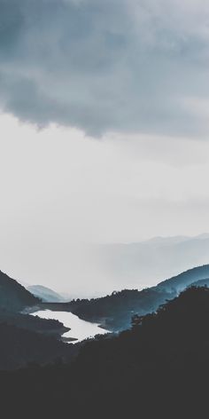 the mountains are covered in dark clouds and some water is visible on the far side