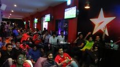 a large group of people sitting in a room with red walls and stars on the wall