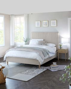 a bedroom with white walls and wood flooring is pictured in this image, there are pictures on the wall above the bed