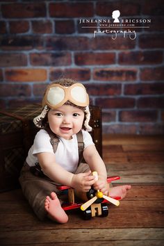 a baby is sitting on the floor playing with toy planes and smiling at the camera