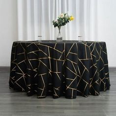 a black table cloth with gold lines on it and a vase filled with yellow flowers