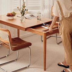 a woman standing in front of a wooden table