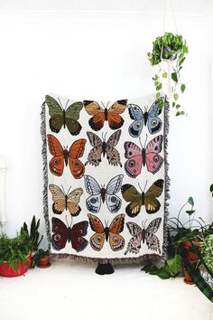 a blanket with butterflies on it sitting next to potted plants and houseplants