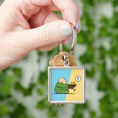 a hand holding a keychain with a cartoon character on the front and back