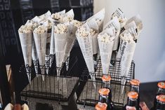 there are many cups with popcorn in them on the table next to some soda bottles