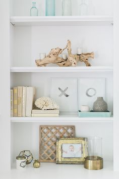 white shelves with pictures, candles and other decorative items on them in a living room