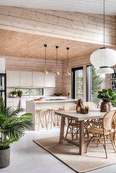 a dining room table and chairs in front of an open kitchen with wooden ceilinging