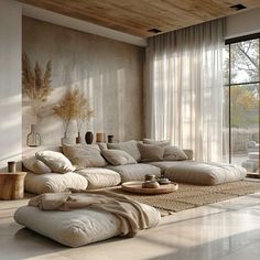 a living room filled with lots of pillows and furniture next to a large glass window