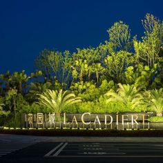 an illuminated sign in front of trees and bushes