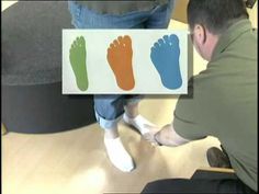 a man sitting on top of a wooden floor next to a person with their feet up