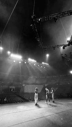 some kids are playing basketball in an empty arena with lights shining on the bleachers