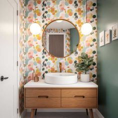 a bathroom with a sink, mirror and lights on the wall above it is decorated in pastel colors