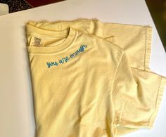 two yellow t - shirts sitting on top of a white table next to each other