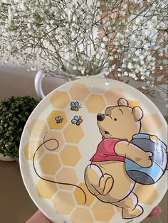 a paper plate with a drawing of a bear and bees on it, in front of a potted plant