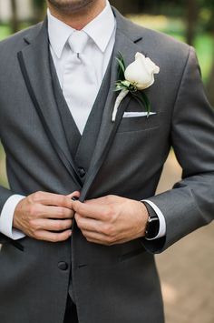 a man in a gray suit with a white rose on his lapel