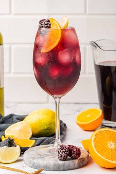 a glass filled with red wine and garnished with lemons, raspberries, and blackberries