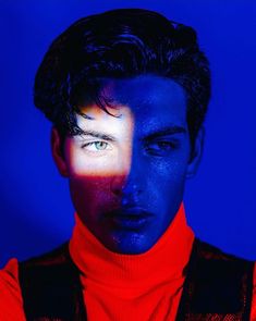 a man with dark hair and blue skin wearing a red turtle neck sweater