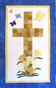 a quilted wall hanging with flowers and a cross on the front, butterflies in the background