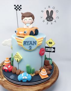 a cake that is on top of a wooden plate with cars and signs around it