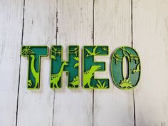 the word'the o'is made out of wood and painted with green dinosaurs