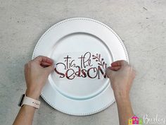 two hands holding a white plate with the words tis the season painted on it,