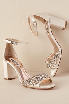 a pair of white high heeled shoes with crystal embellishments