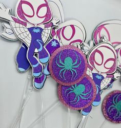 purple and blue cupcake toppers with spiderman on them are sitting next to each other