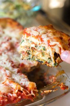 someone is taking a slice of pizza out of the casserole dish with their hand