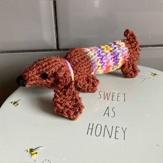 a crocheted toy dog on top of a white plate with the words sweet as honey written below it