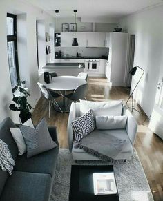 a living room filled with furniture next to a kitchen and dining room table on top of a hard wood floor