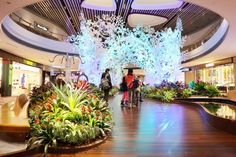 people are standing in the middle of a mall with flowers and plants on display behind them