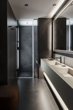 a modern bathroom with two sinks and a large mirror on the wall, along with a bench