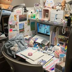 a cluttered desk with a laptop computer and lots of stuff on top of it