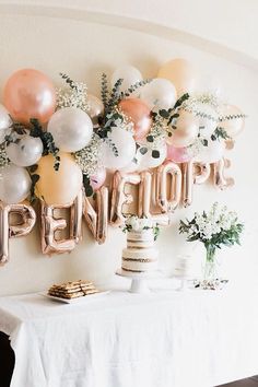 a table topped with balloons and cake next to a wall