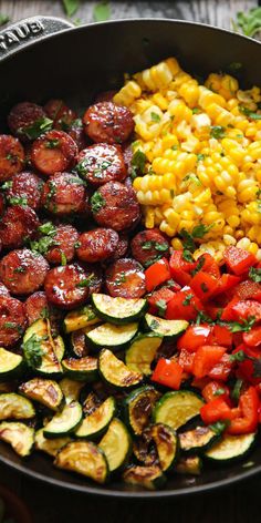 a pan filled with vegetables and corn on the cob next to other food items