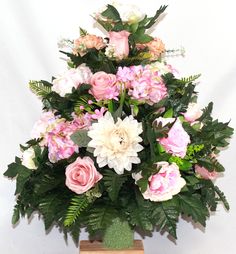 a vase filled with lots of pink and white flowers on top of a wooden stand