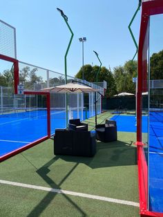 an outdoor tennis court with chairs and umbrellas