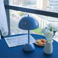 a blue table topped with a plate of food and a vase filled with white flowers