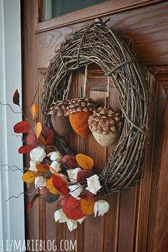 a wreath with leaves and acorns hanging on a door