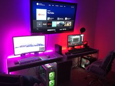 a computer desk with two monitors, keyboard and mouse on it in front of a purple wall