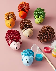 pine cones, acorns and paint are arranged on a pink surface