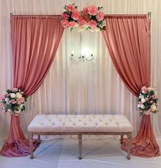 a white bench with pink curtains and flowers on it