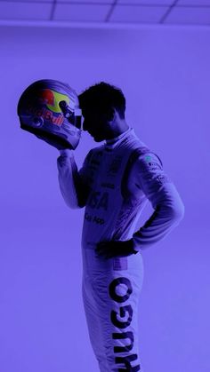 a man holding a helmet while standing in front of a purple background