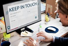 a man sitting at a desk working on a computer with his hands on the keyboard