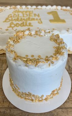 a white cake with gold sprinkles sitting on top of a wooden table