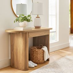 a wooden table topped with a mirror next to a lamp and a wicker basket