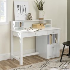 a white desk with some books and a vase on it next to a black chair